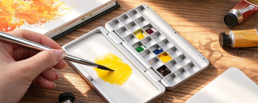 Mixing yellow watercolor paint on ceramic white surface of Fuumuui 24-well aluminum palette glacier silver.