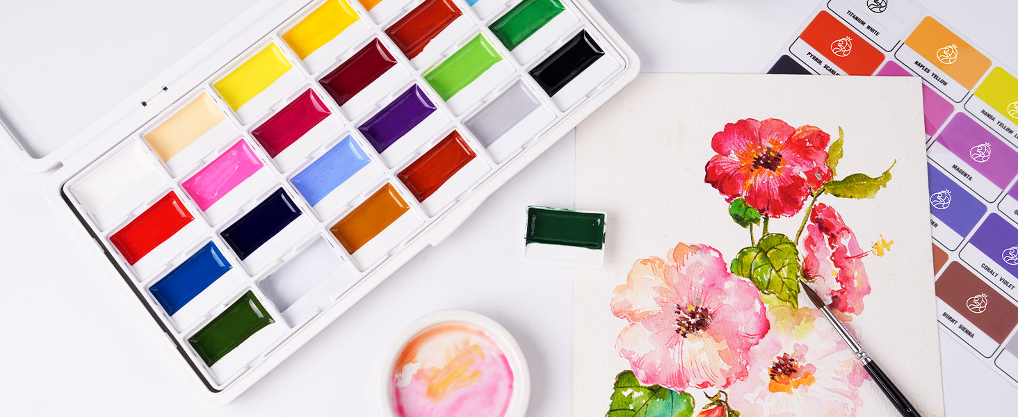Professional Watercolor Paint Set with vibrant pigments in a white plastic palette, featured next to a floral painting on textured Cold Press paper with a fine Miniature Paint Brush for detail work.