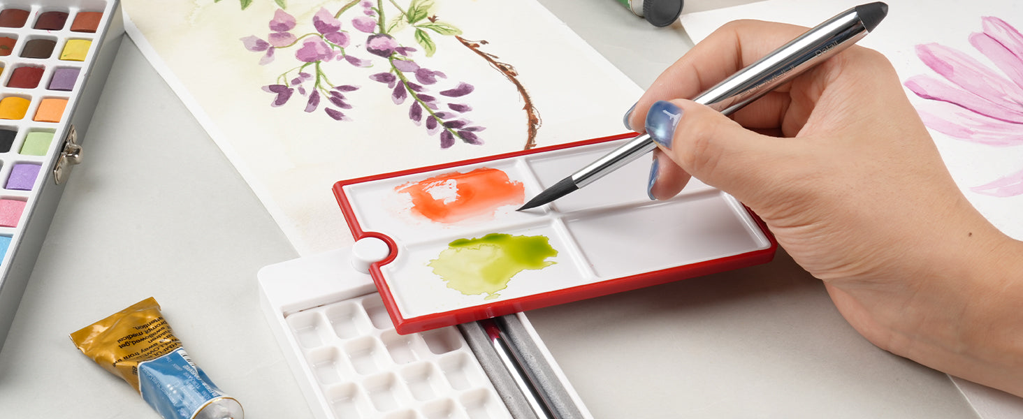 Professional artist using a silver Travel Watercolor Detail Brush to mix paint in a plastic Travel Palette, featuring a Watercolor Paint Set and floral illustration on 140lb Cold Press 100% Cotton paper.