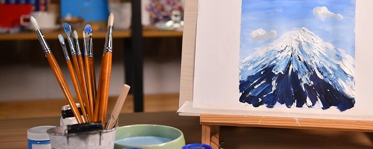 Professional natural hog bristle paint brush set with red handles for oil and acrylic paint. Brushes in a studio next to an impasto mountain painting on an easel and brush cleaner, ideal for professional artists.