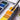 Kolinsky Sable travel watercolor brush with a fine point dipping into an orange pan in a professional watercolor paint set. Silver travel pocket brush for professional artists and detailed watercolor painting.