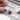 Hand organizing empty white plastic pans into a compact grey travel palette, perfect for creating a custom watercolor paint set for professional artists and beginners.