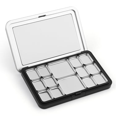 Open portable metal travel palette for watercolor paint featuring 12 various sized silver pans and a large mixing area in the lid, perfect for professional artists and beginners.