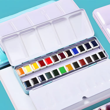 Ensemble de peinture aquarelle 24 couleurs Fuumuui ouvert dans une boîte en métal bleu clair, présentant des godets de peinture individuels vibrants et des godets de mélange intégrés.