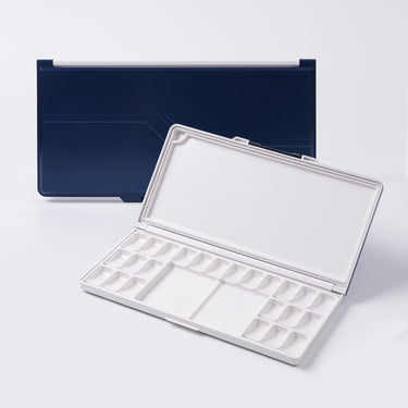 Fuumuui Art Supplies dark blue airtight plastic paint palette with lid, open to display 24 wells and mixing areas for watercolor and acrylic paints.