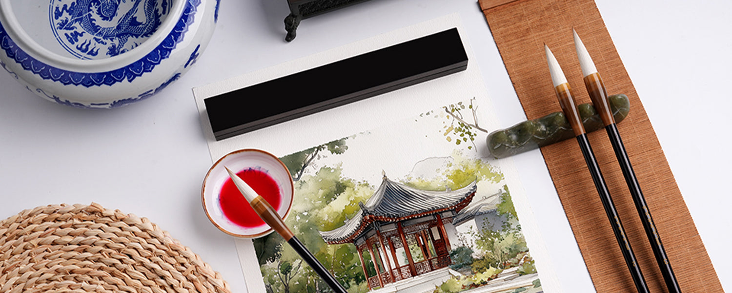 Chinese Calligraphy Brush set with white hair dipped in red watercolor paint on textured cold press paper. Landscape watercolor painting with professional artist supplies, ceramic brush cleaner, and stone brush rest.