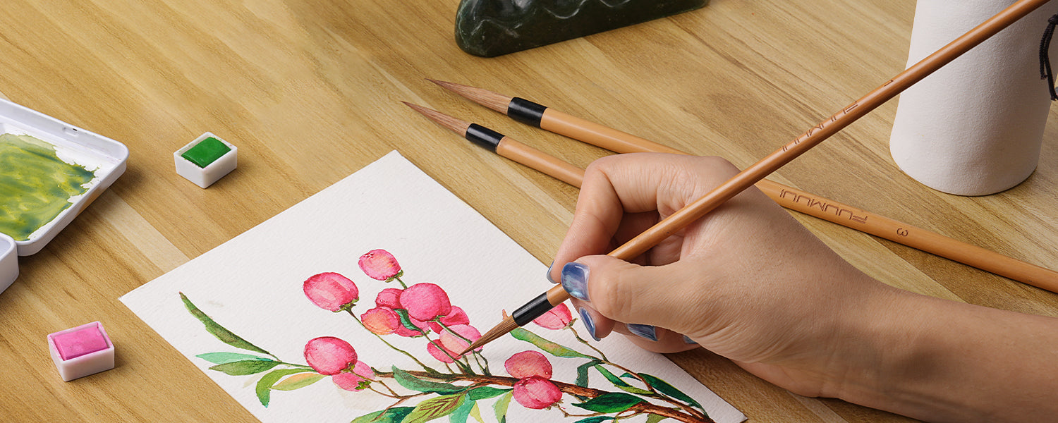 Artist painting pink flowers with a Fuumuui Chinese Calligraphy Brush on cold press watercolor paper. Professional natural hair watercolor brush set with fine detail tips and vibrant watercolor paint pigments.