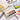 Fuumuui Portable 12-color solid watercolor paint set with built-in palette and brush, displayed open on a white surface alongside vibrant Fuumuui Art Supplies watercolor paintings and a sketchbook.