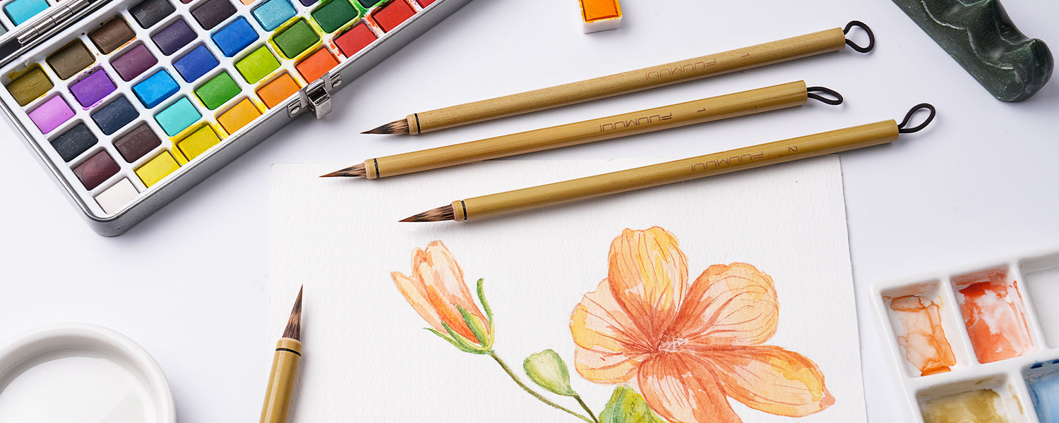 Fuumuui Chinese Calligraphy Brush set with natural bristles on a floral watercolor painting. Features a metal watercolor paint set, plastic palette, and 100% cotton cold press paper for professional artists.