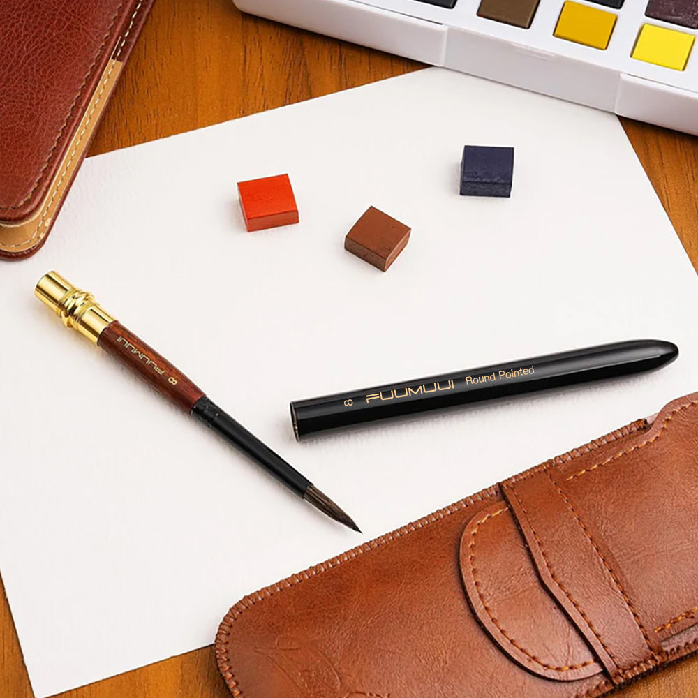 Fuumuui travel watercolor brush with its cap removed, ready for use with solid watercolor paints and a leather carrying case for outdoor art.