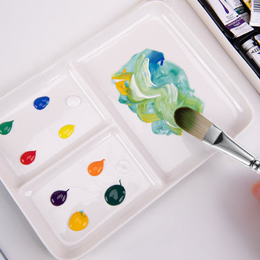Fuumuui Keramik-Künstlerfarbpalette mit mehreren Wells mit bunten Farbtropfen und einem Pinsel, der lebendige Farbtöne mischt.