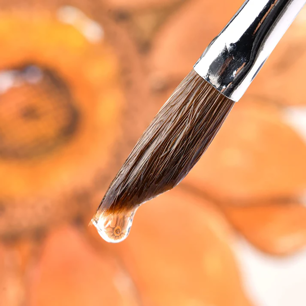 A sable watercolor brush tip holding a droplet of water, excellent water-carrying capacity.