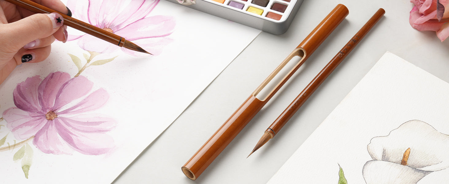 Professional artist painting floral illustrations on 100% cotton cold press paper with a Kolinsky Sable watercolor brush. Set includes a travel pocket brush and watercolor paint set on a white workspace.