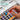 Hand holding a vibrant red pan from a Fuumuui 50-color portable watercolor set, showcasing finely milled, acid-free, lightfast pigments for maximum vibrancy, natural blending, and lasting brilliance without chalkiness or mud.