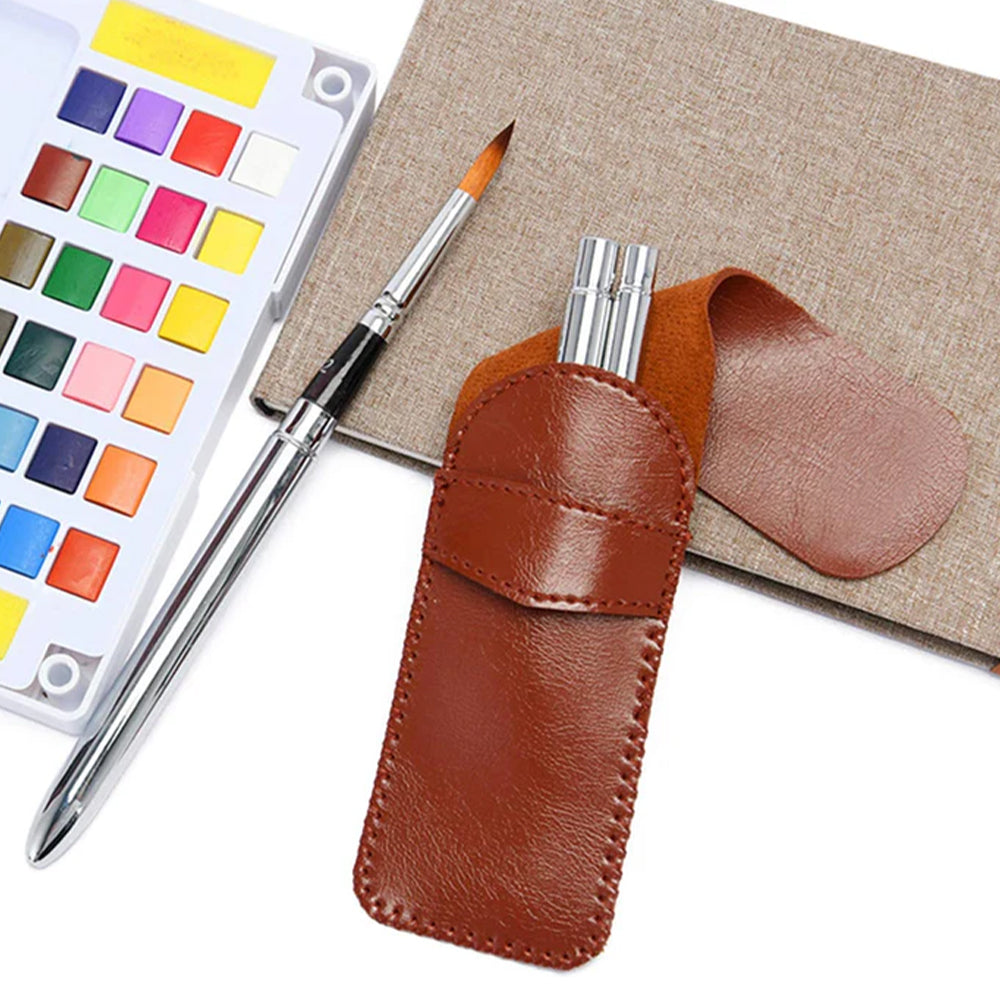 A portable Fuumuui watercolor brush set with its leather case, along with a watercolor palette and a notebook.