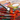 Fuumuui 6pcs Professional Red Sable Watercolor Filbert Brushes, one dipped in orange paint on a vibrant artist's palette.