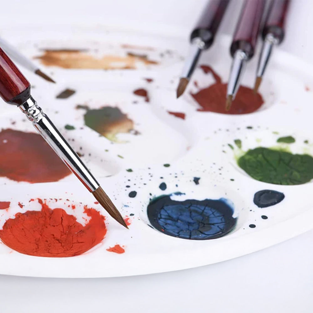Fuumuui detail brush dipping into paint on a paint palette, a versatile tool for creating miniature art and detailed watercolor paintings.