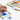 Fuumuui Art Supplies: A hand uses a professional Fuumuui squirrel sable hair bamboo paint brush, part of the 6Pcs Dagger Flat Round Detail set, to paint blue watercolor flowers on white paper. A palette with vibrant Fuumuui watercolor paints and additional brushes are visible in the background.