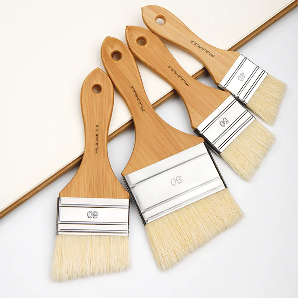 Fuumuui professional bristle brushes arranged on a sketchbook, large flat heads and durable wooden handles for artists.