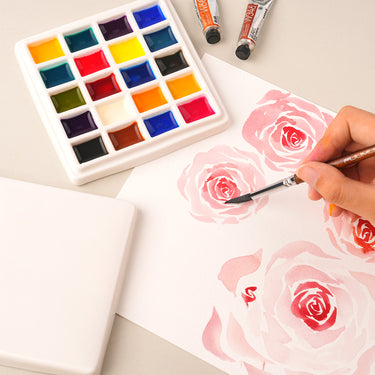 Palette d'aquarelle en céramique à 20 godets Fuumuui avec couvercle, remplie de peintures vibrantes. Un artiste utilise ce plateau de mélange de peinture en porcelaine pour créer un art de rose à l'aquarelle, idéal pour une utilisation en studio et les fournitures d'art Fuumuui.