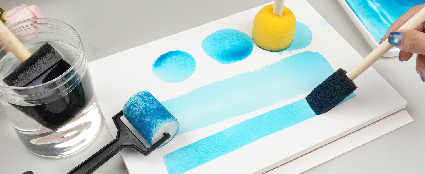 Foam watercolor brush set with sponge roller and pouncer applying blue paint on 140lb cold press paper. Artist using a clear paint brush cleaner jar to rinse tools during a creative session for beginners.