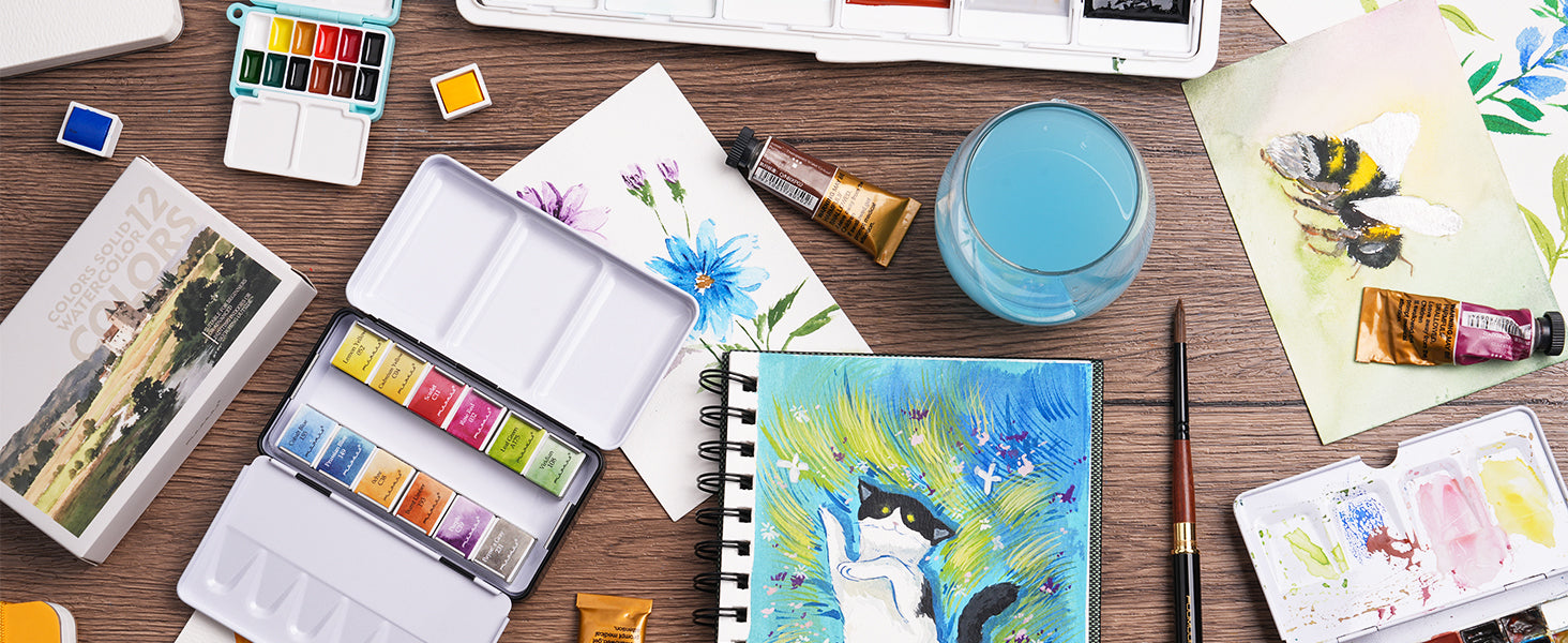 Beginners 12 colors solid watercolor paint set in a metal tin with a squirrel hair watercolor brush, spiral sketchbook, and travel palette. Non-toxic pigment watercolor painting supplies for artists.