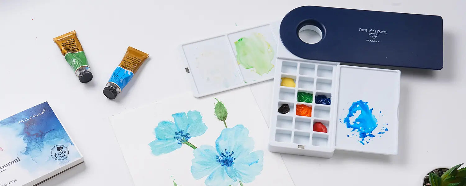 Fuumuui swivel watercolor palette set with paint tubes, mixing tray, and blue flower painting.