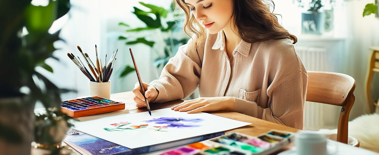 Professional artist painting on Fuumuui 100% cotton cold press 140lb/300gsm watercolor paper block. A vibrant watercolor paint set and assorted watercolor brushes are used for a detailed floral painting.