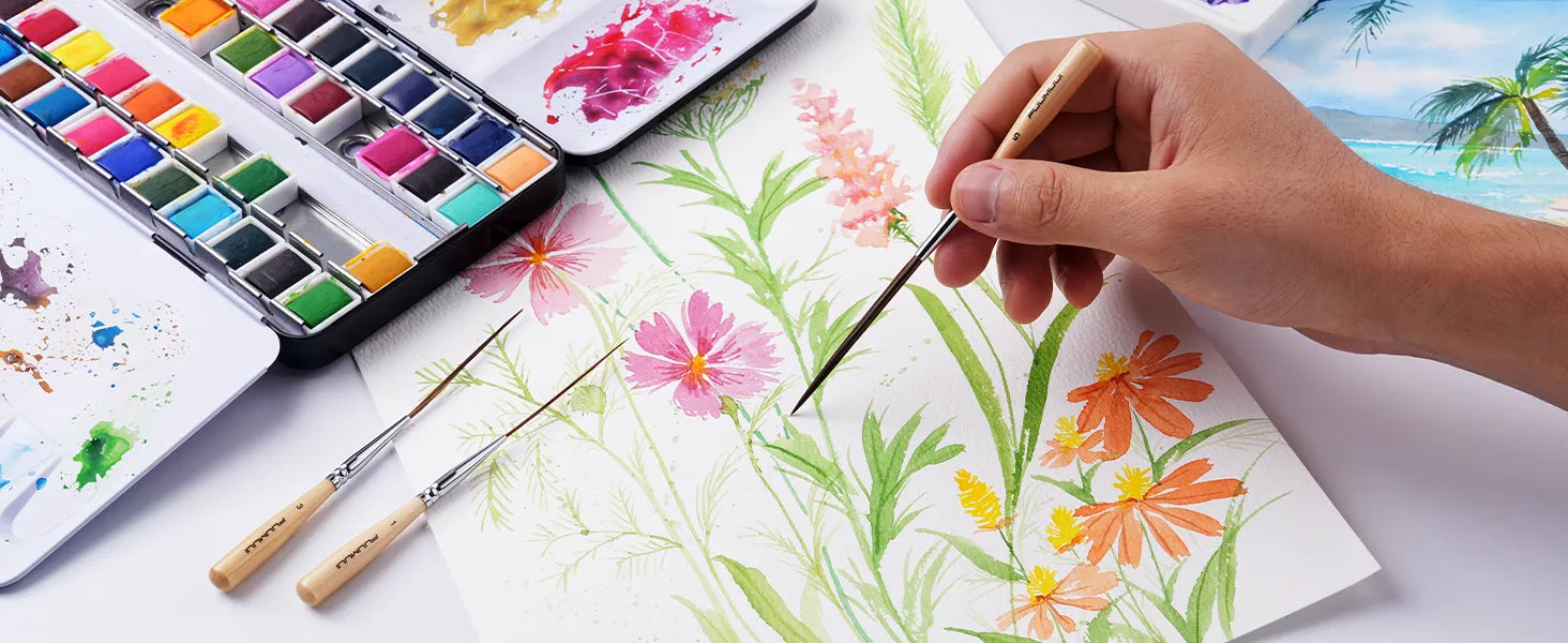 Professional artist using a Fuumuui Long Liner Brush (Size 5) to paint floral details on cold press watercolor paper. Synthetic nylon detail brush set with sizes 1 and 3 next to a vibrant watercolor paint set.