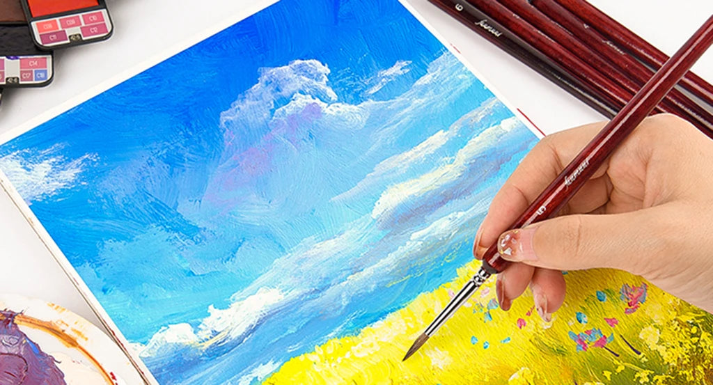 Professional artist using a Fuumuui Kolinsky sable detail brush for a landscape painting. This detail brush set is ideal for acrylic paint, oil paint, or gouache on a cold press watercolor sketchbook or block.