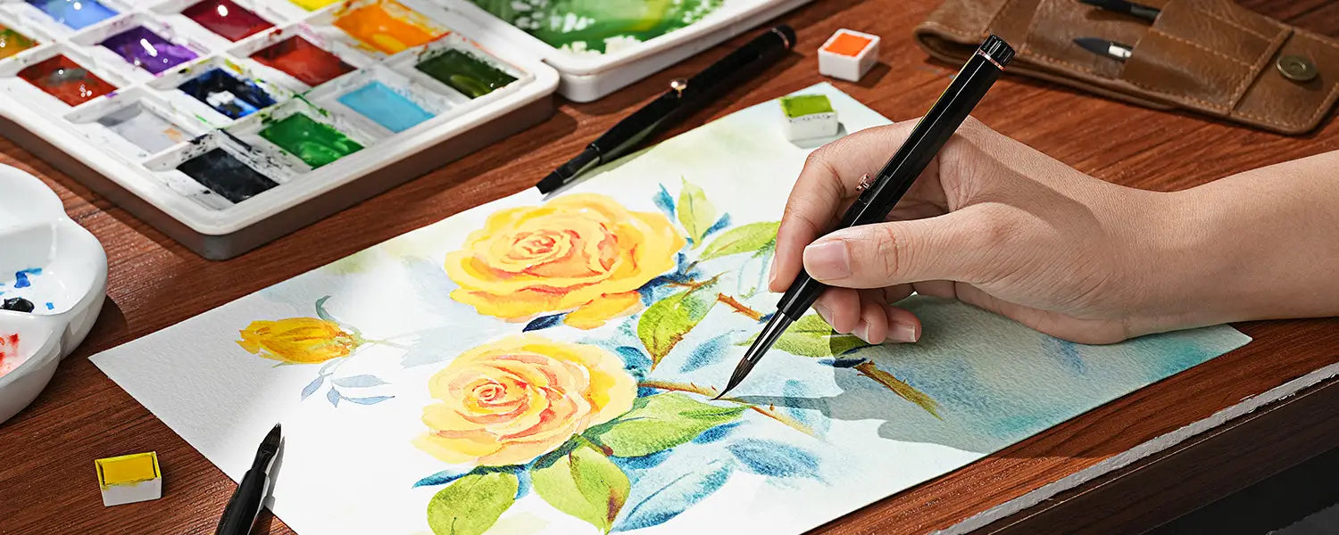 Painting yellow roses with a Fuumuui retractable watercolor brush, surrounded by a palette and other art supplies.