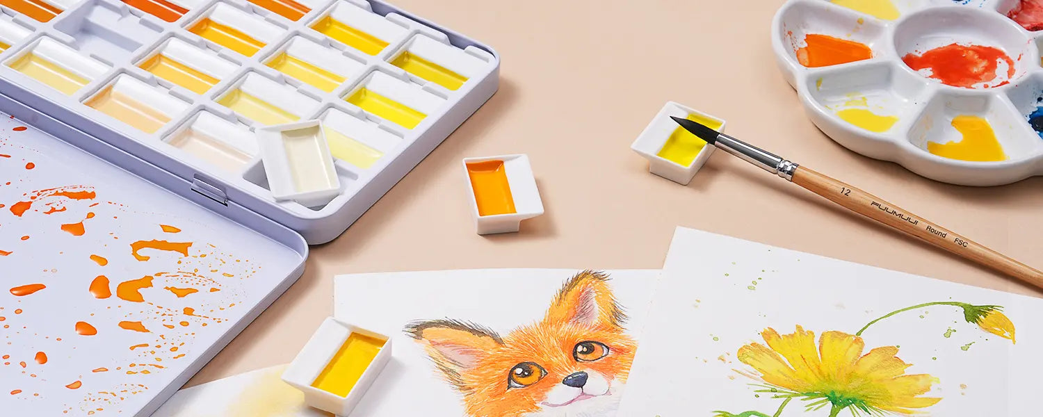 Creative workspace with Sunlit Yellow watercolor set, paintbrushes, flower sketches, and fox artwork.
