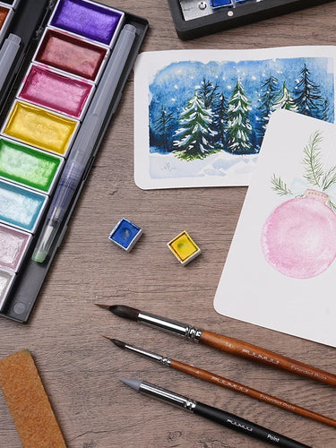 Fuumuui Extended Point squirrel hair watercolor brushes size 14 and 4, metallic watercolor paint set, and 100% cotton cold press paper. Professional art supplies for painting winter landscapes and holiday ornaments.