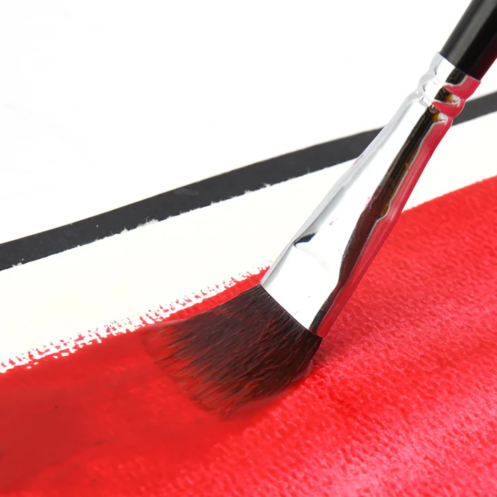 A Fuumuui watercolor brush with a flat tip applying a thick, vibrant red stroke on paper.