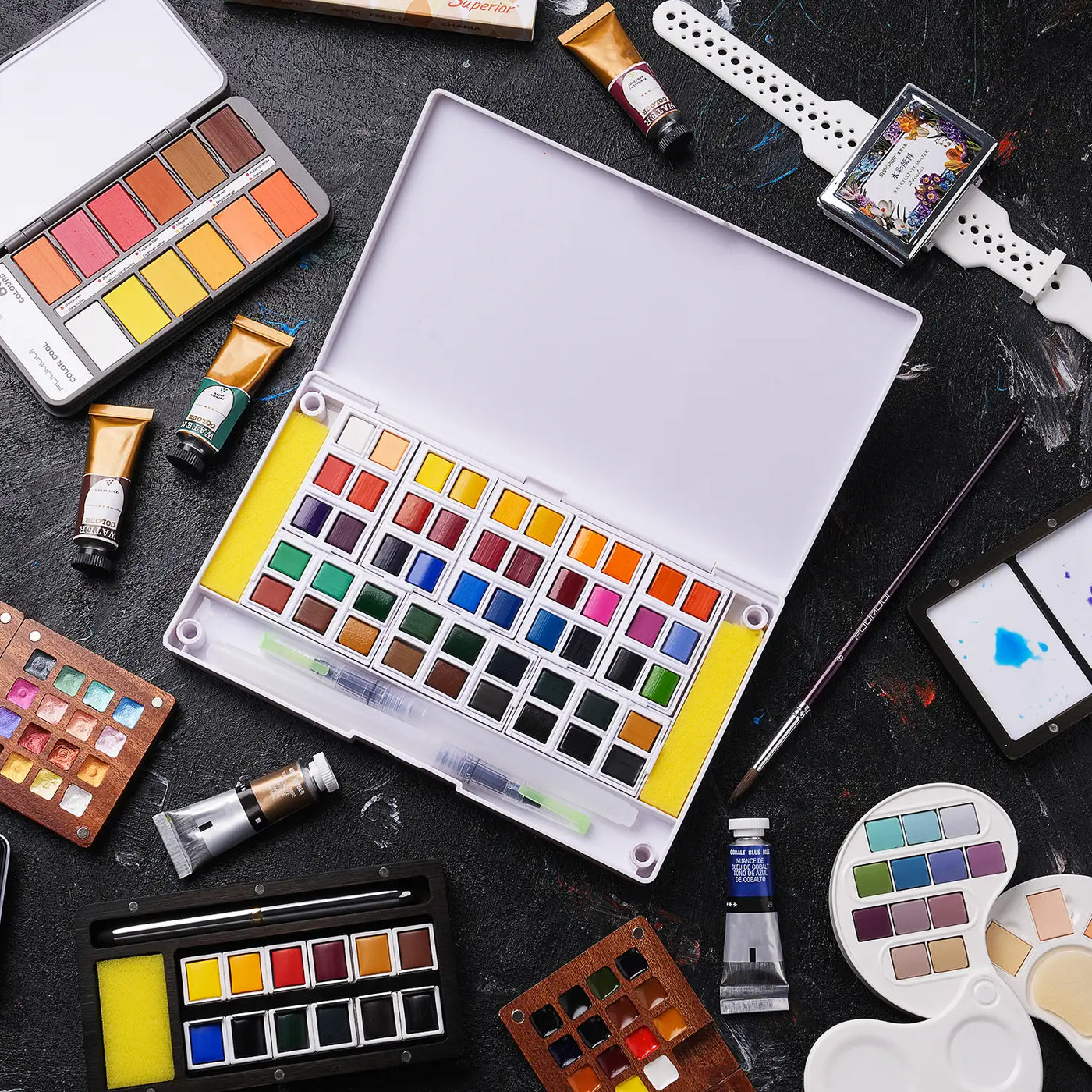 Fuumuui watercolor paint set with a large plastic travel palette of pans, pigment tubes including Cobalt Blue Hue, synthetic watercolor brushes, and mixing palettes for professional artists and beginners.