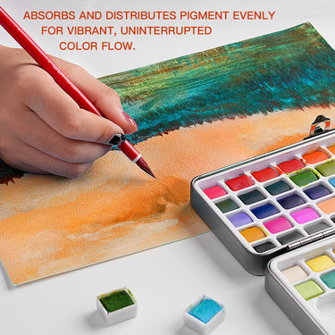 Artista che dipinge con un pennello per acquerello in pelo di capra rosso FUUMUUI, realizzato a mano (manico rosso) su carta, dimostrando eccellente assorbimento e flusso uniforme del pigmento da un set di godet per acquerello per una vivace scena sulla spiaggia.