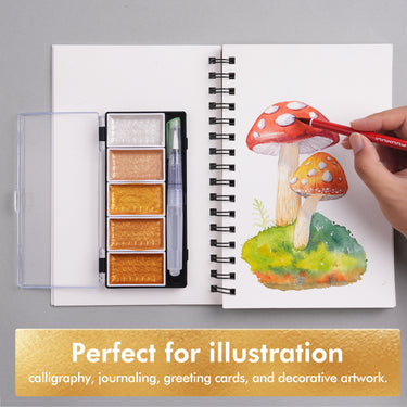 Set di colori ad acquerello metallici ad alte prestazioni FUUMUUI (bianco, oro, bronzo) con pennello ad acqua, accanto alla mano di un artista che dipinge un'illustrazione di funghi luccicanti in un album da disegno a spirale, evidenziando le forniture artistiche Fuumuui per illustrazione, calligrafia, journaling e opere d'arte decorative.