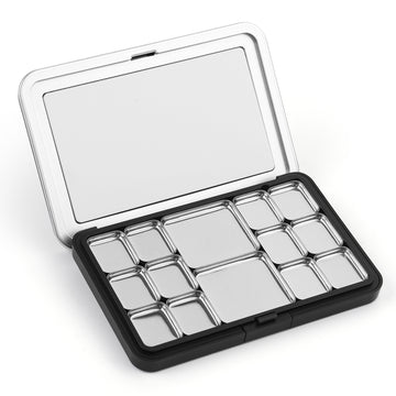 Open portable metal travel palette for watercolor paint featuring 12 various sized silver pans and a large mixing area in the lid, perfect for professional artists and beginners.