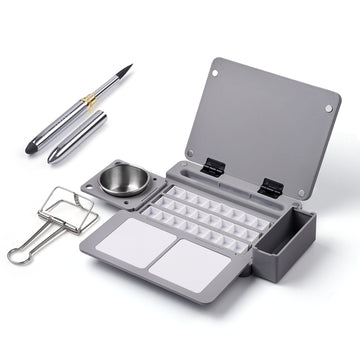 Grey travel plastic palette with 15 pans, mixing areas, metal water cup, and clip. Includes a Fuumuui metal travel watercolor brush with synthetic nylon detail brush tip for professional artists and beginners.