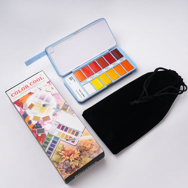 Fuumuui 60-Color Watercolor Paint Set, featuring the light blue portable palette open to reveal vibrant paint pans, its colorful retail packaging box, and a black velvet carrying bag, all displayed on a clean white surface.