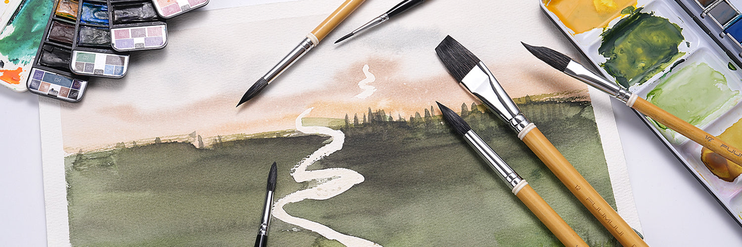 Professional Fuumuui squirrel hair watercolor brush set including size 12 round and 1/2 inch flat brushes on textured cold press paper. Shown with a landscape painting and watercolor paint set for artists.