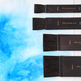 Fuumuui 4er-Pack Aquarell-Flachpinsel (20mm, 30mm, 40mm, 50mm), ausgestellt auf einem blauen Aquarellhintergrund, perfekt für Lasuren, Hintergründe und große Malbereiche.