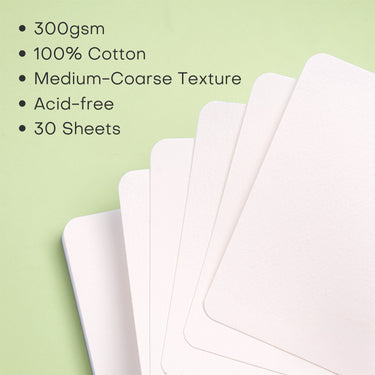 Fuumuui - Blocco per acquerello 5.5x5.5 pollici che mostra una pila a ventaglio di fogli di carta da 300gsm, 100% cotone, pressata a freddo, a grana medio-grossa, senza acidi (30 fogli) su uno sfondo verde.