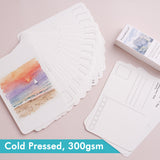 FUUMUUI Aquarellpostkarten, 100% Baumwolle & kaltgepresstes 300 g/m² Kunstdruckpapier. Ein aufgefächerter Stapel weißer Postkarten wird gezeigt, wobei eine ein Aquarell-Sonnenuntergangsgemälde und eine andere ihre versandfertige Rückseite zeigt.