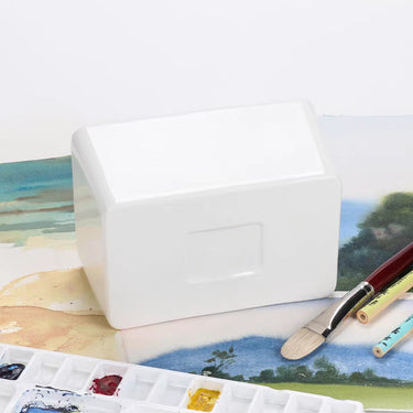 Bol de lavage de pinceaux en céramique Fuumuui, rectangulaire blanc, présenté avec une palette de peinture et des pinceaux d'artiste.