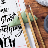 Fuumuui Chinese Calligraphy Wolf Sheep Mix Brushes on a green mountain-shaped rest, with ink stone and paper.