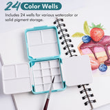 Boîte de palette d'aquarelle pliante à double couche Fuumuui Art Supplies avec 24 godets et 7 zones de mélange, ouverte sur un carnet de croquis avec un pinceau. Ce plateau de peinture compact et portable est idéal pour les voyages et l'utilisation en studio.