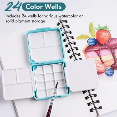 Boîte de palette d'aquarelle pliante à double couche Fuumuui Art Supplies avec 24 godets et 7 zones de mélange, ouverte sur un carnet de croquis avec un pinceau. Ce plateau de peinture compact et portable est idéal pour les voyages et l'utilisation en studio.