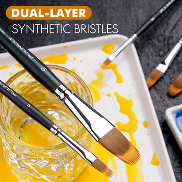 Pennelli filbert sintetici a doppio strato Fuumuui per acquerello e acrilico, con punte marroni e gialle, esposti sulla tavolozza di un artista con pittura e in un bicchiere d'acqua.