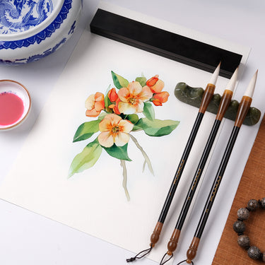 Fuumuui professionelle Kalligraphiepinsel für Aquarell- & Tuschemalerei, ausgestellt mit einem floralen Kunstwerk, einer Pinselablage und traditionellen Künstlerbedarf.
